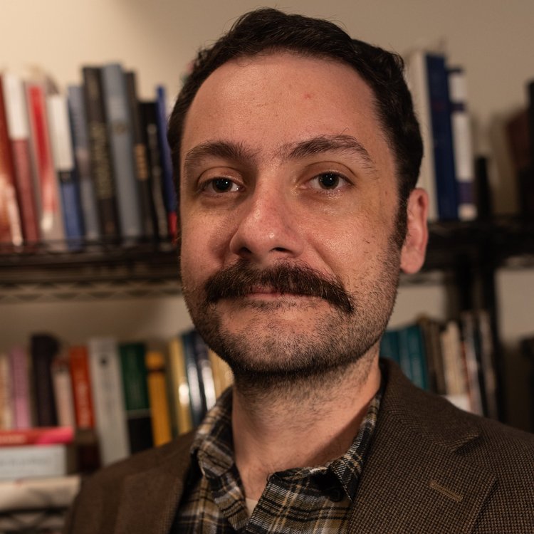 Self-portrait of Andrew L Smith in front of bookshelves
